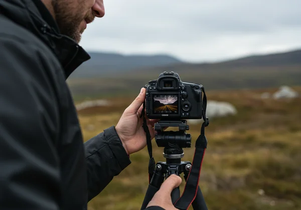 Photographer manually focusing camera in a landscape